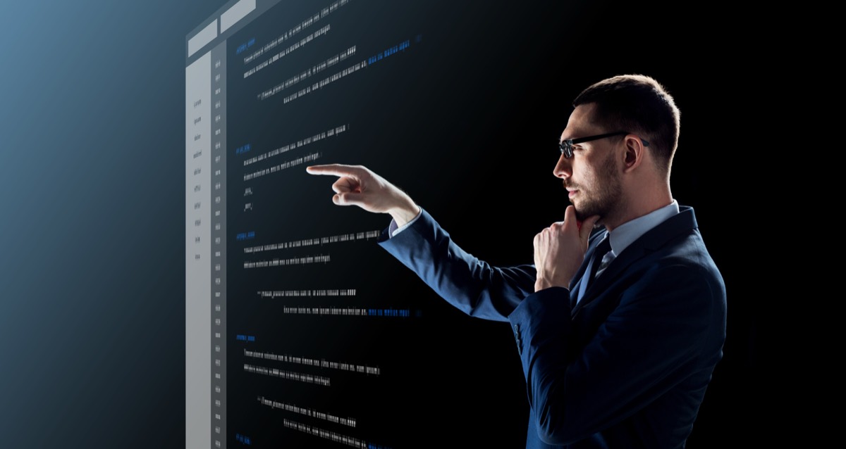 Stacks of printed source code pages beside a stock-trading terminal