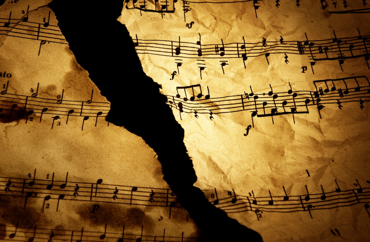 Vintage sheet music spread across the closed lid of a grand piano