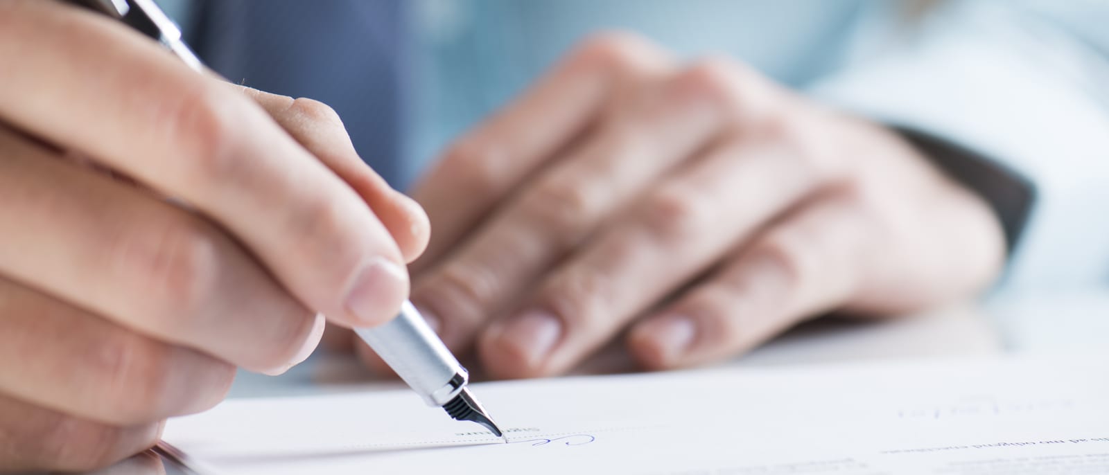 A signed contract and pen resting on a desk in soft light