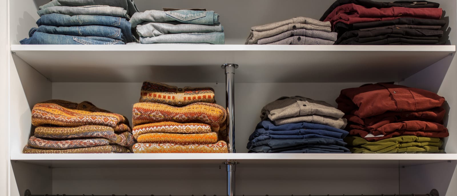 Folded stacks of men's slacks and shirts on retail shelving
