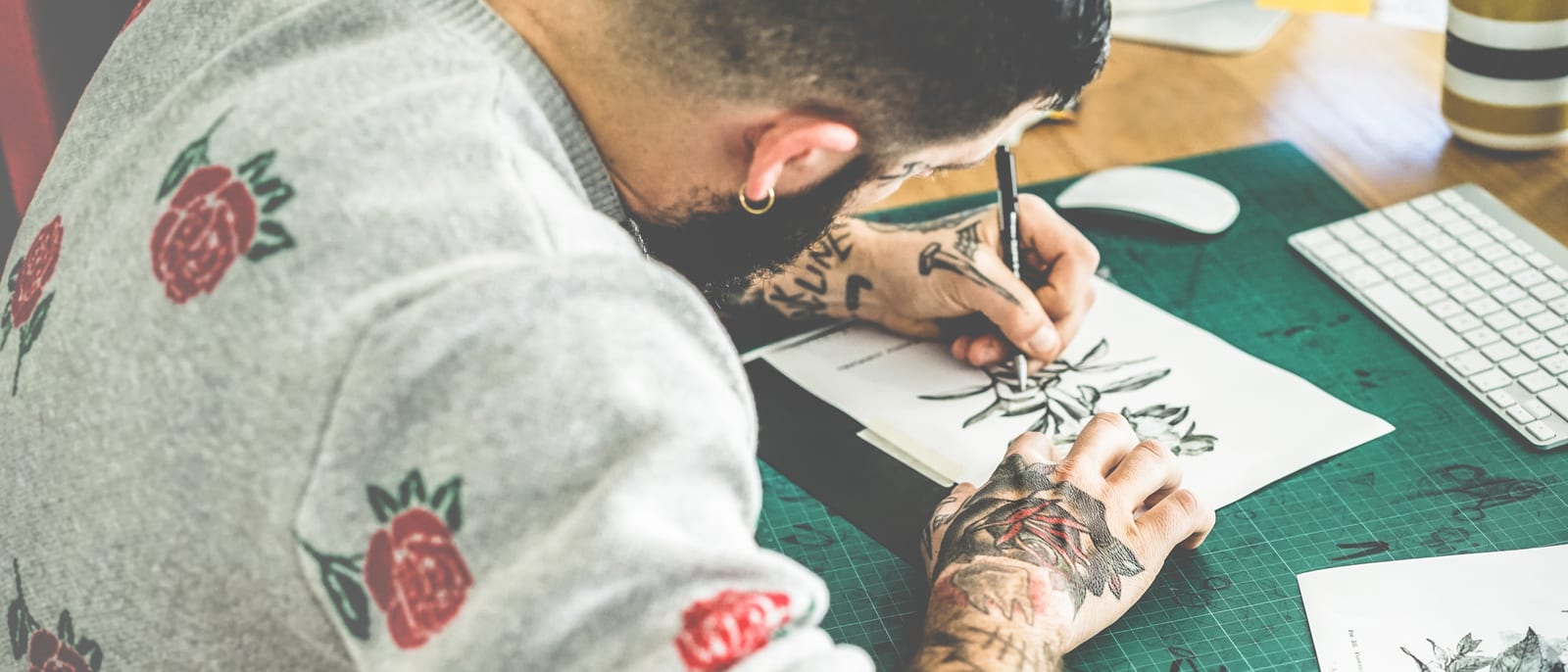 A tattoo artist's hand inking an intricate design on a client's back