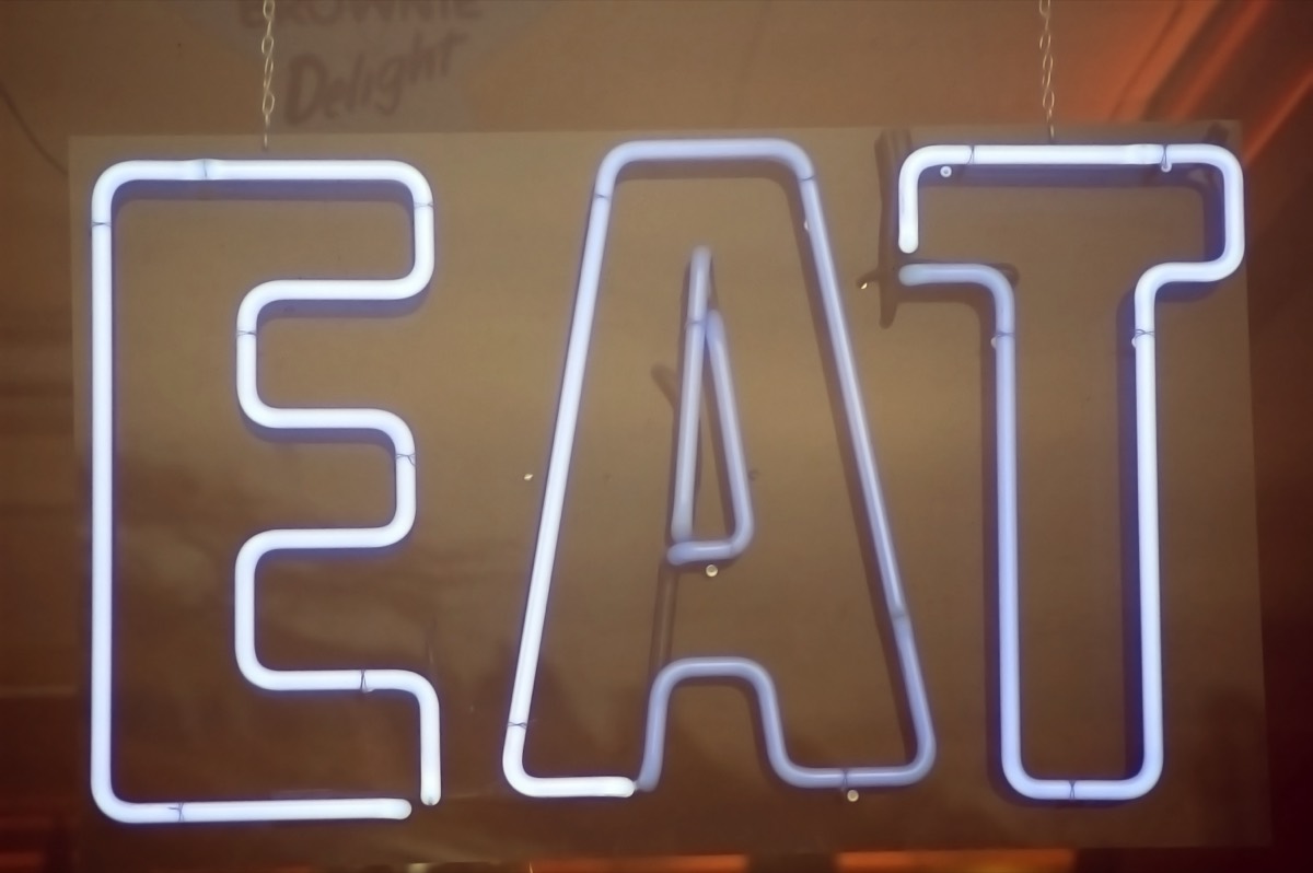 Vintage roadside hamburger stand with a glowing neon sign at dusk