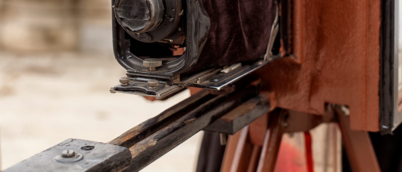 An antique large-format bellows camera on a wooden tripod in a portrait studio