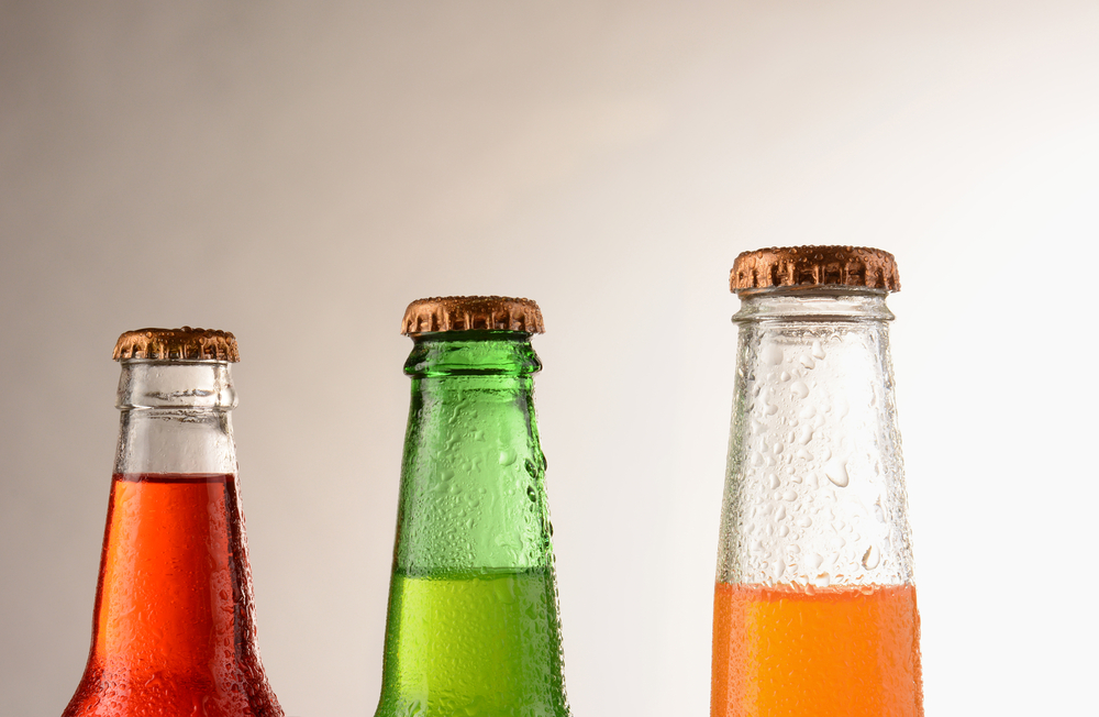Rows of vintage glass soda bottles on a wooden shelf