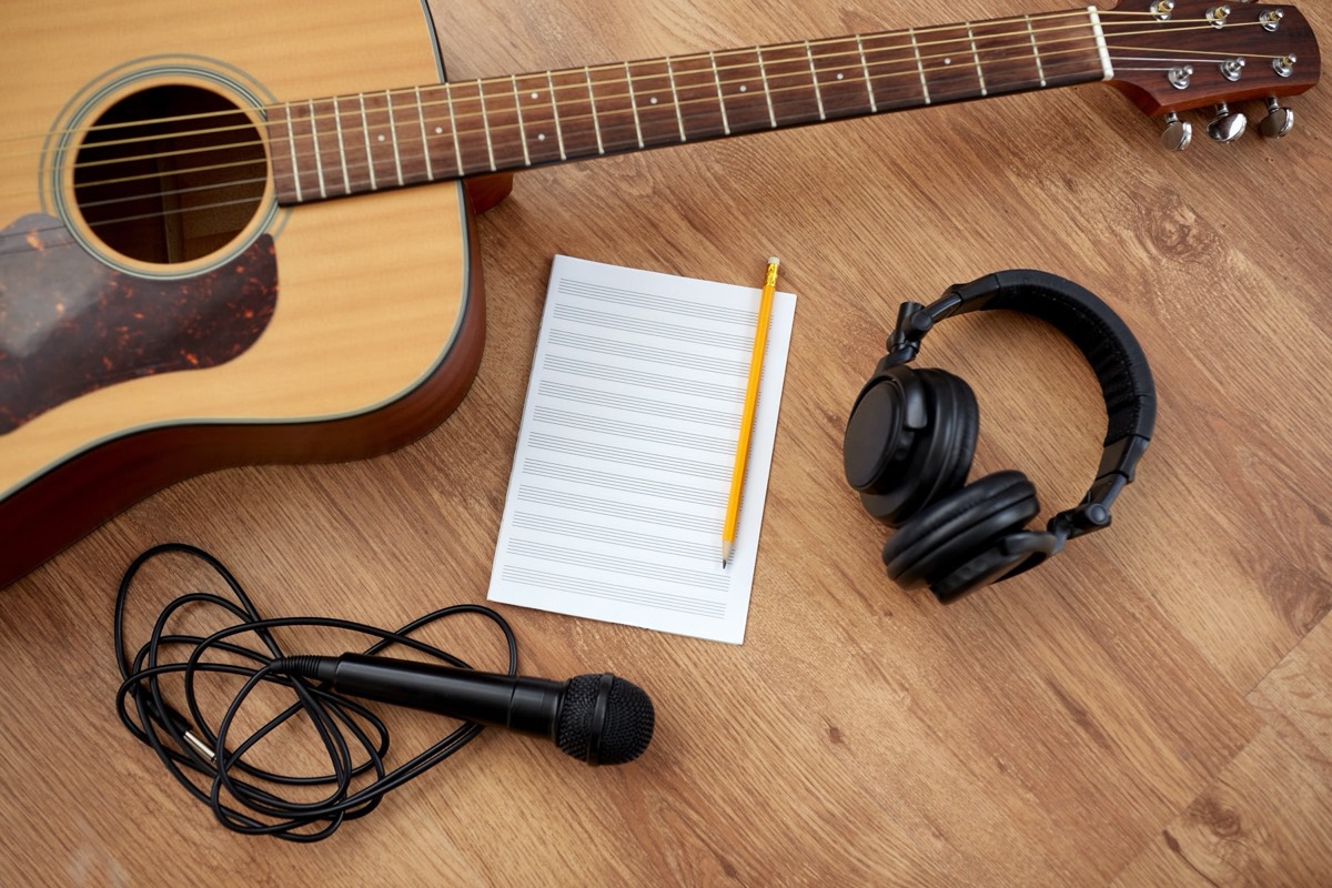 A songwriter's handwritten lyric sheet beside an acoustic guitar