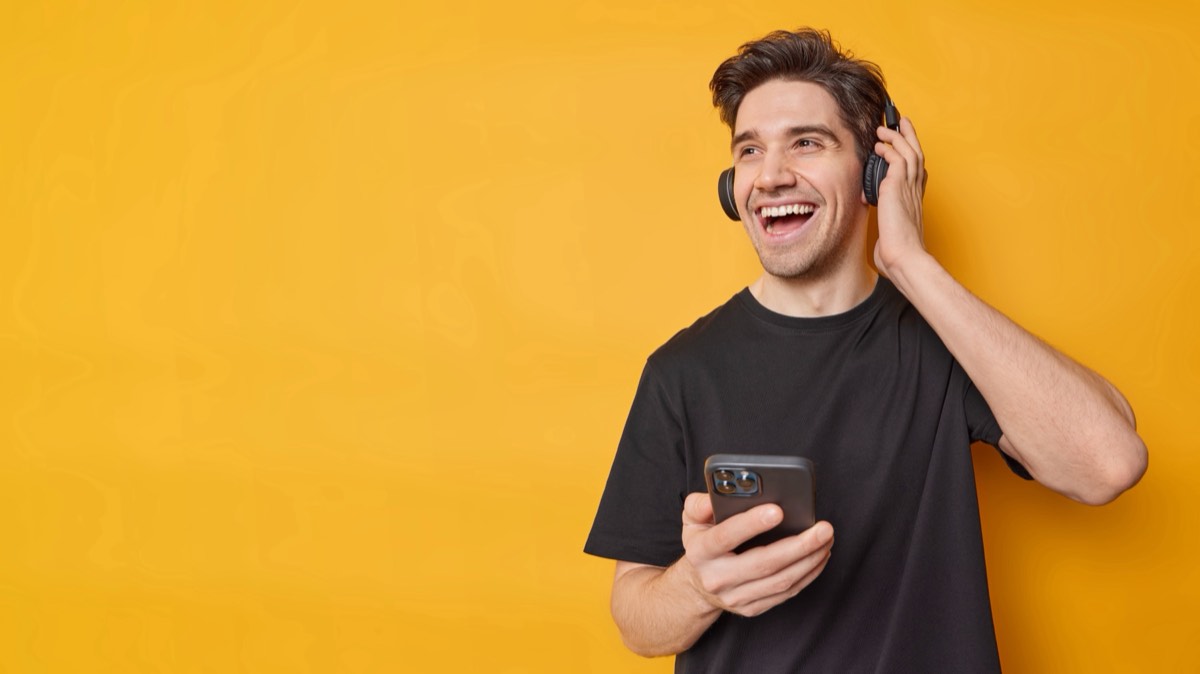 A person holding a smartphone showing a music streaming playlist