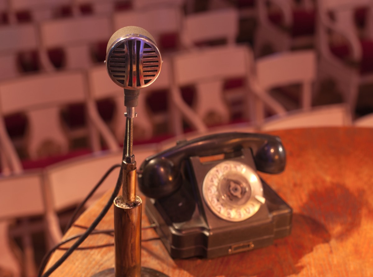 A vintage microphone on an empty stage under a single spotlight