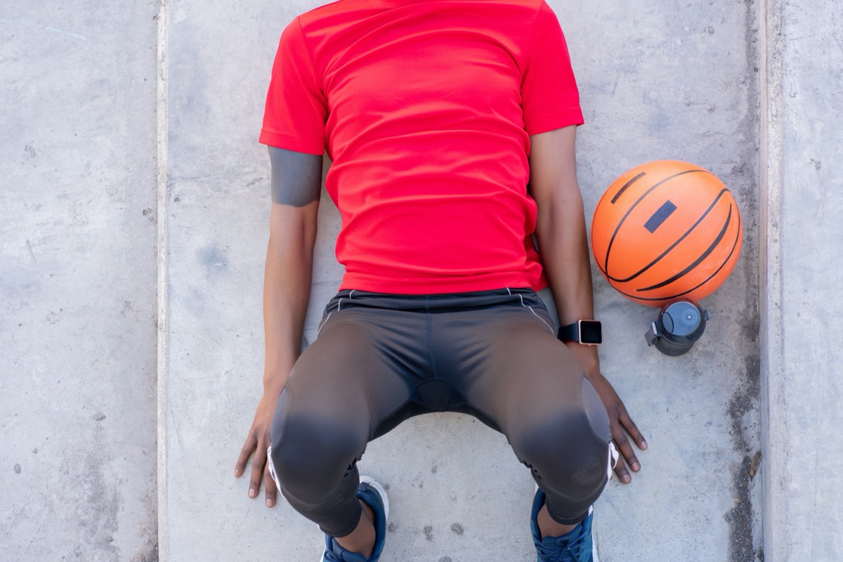 A basketball player's tattooed arm gripping a basketball under arena lighting
