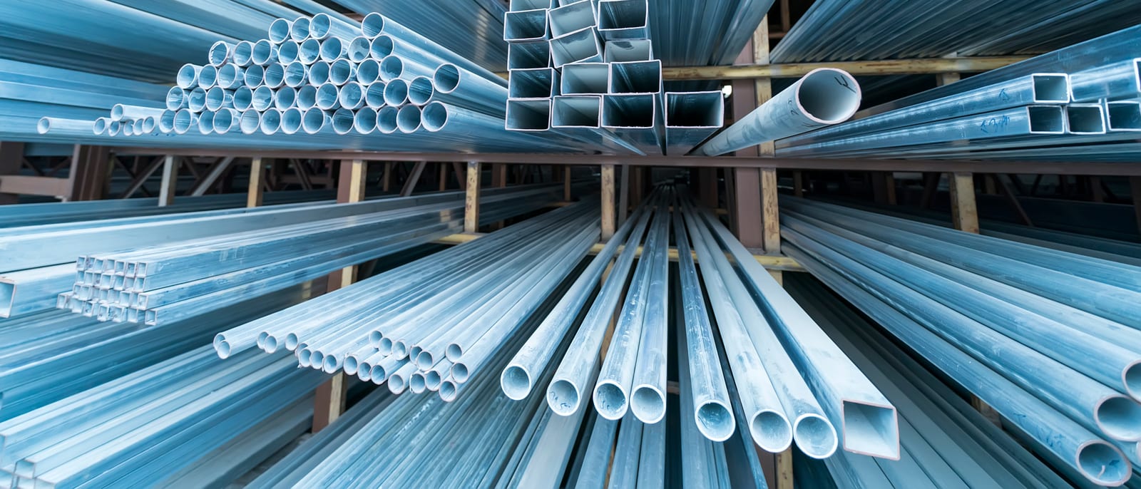Stacks of polished steel and specialty alloy pipes in an industrial warehouse