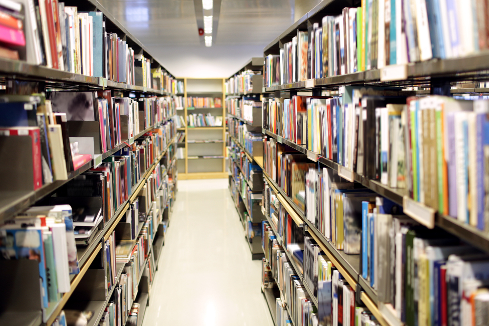 Weathered public library shelves filled with old bound volumes under warm light