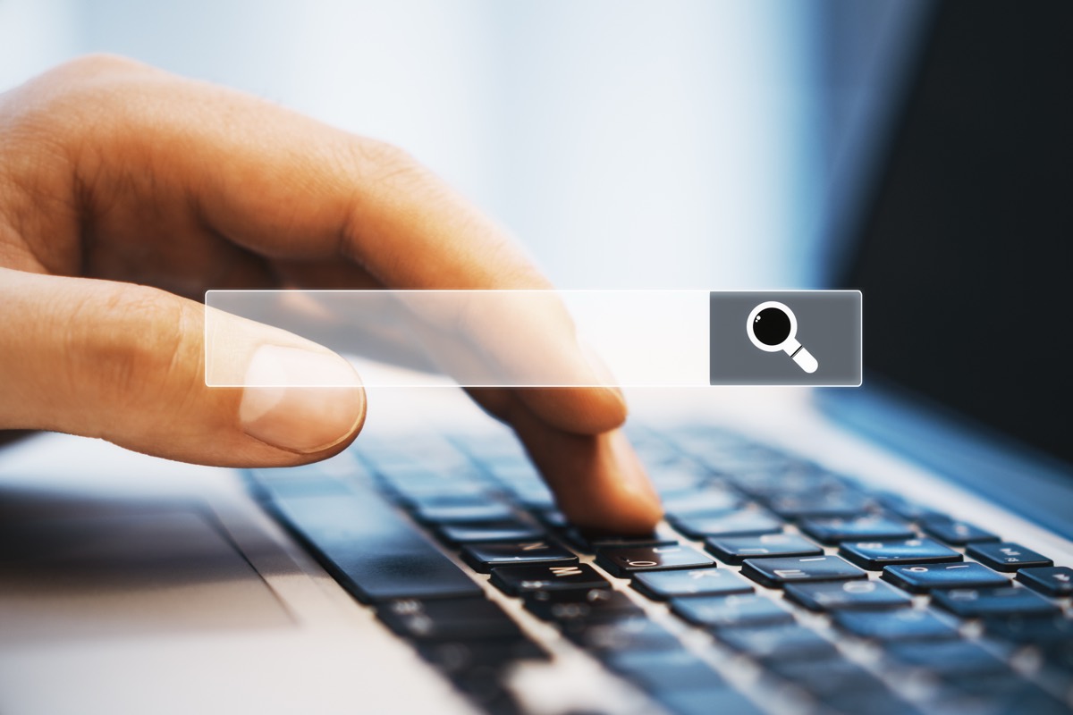Hands typing a query into a search bar on a laptop screen
