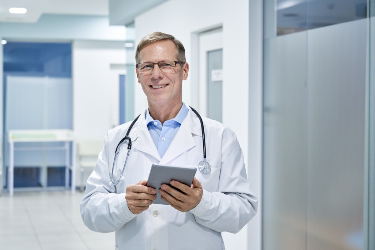 A physician using electronic health record software on a tablet in a clinic