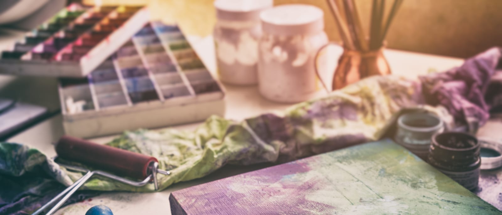 An artist's paintbrush and palette beside a canvas in a sunlit studio