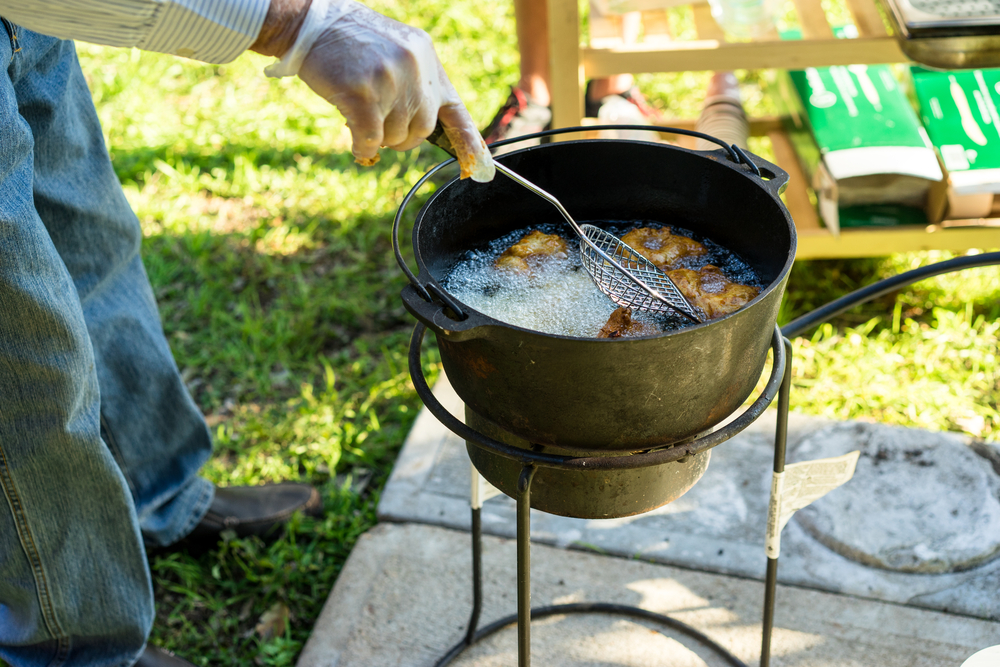 A stainless steel commercial deep fryer basket lowering into hot oil in a kitchen