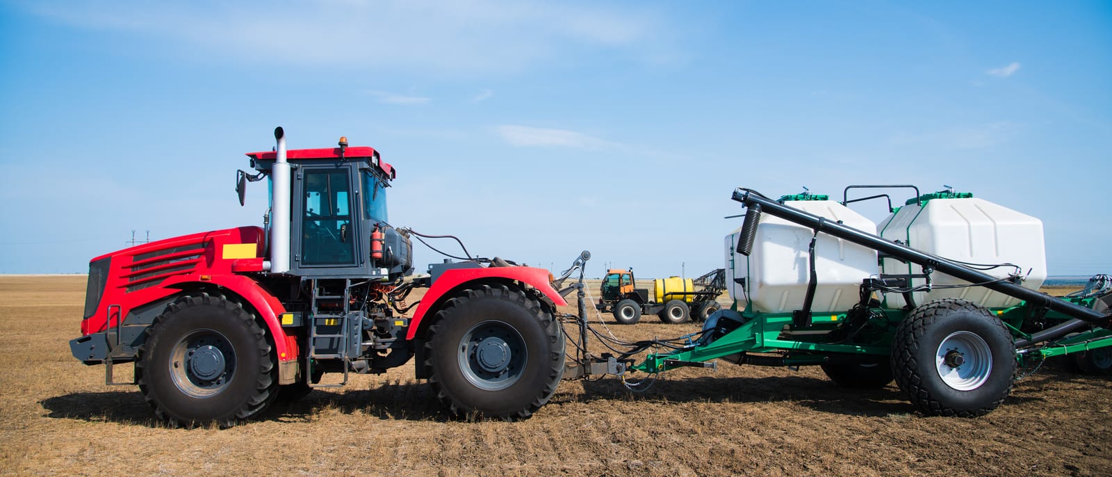 A plow attachment and farm machinery in a field at golden hour