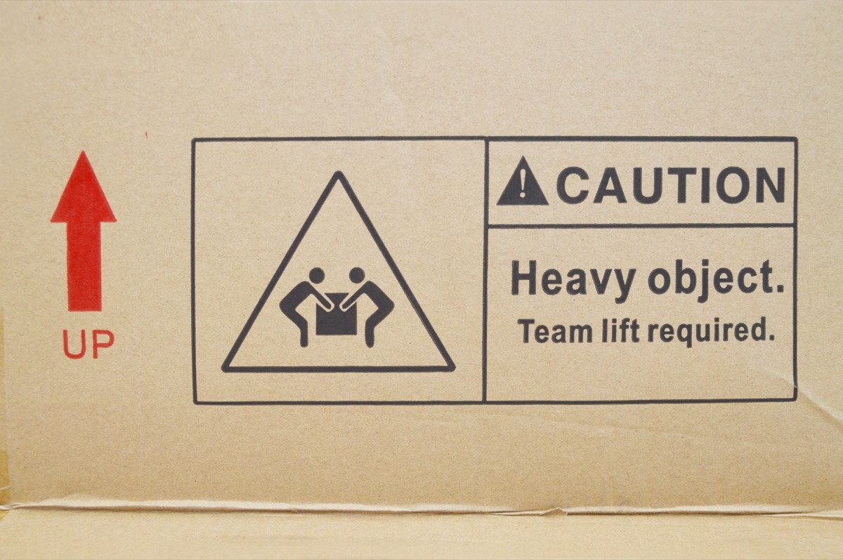 Online seller in a home office packing orders while checking a suspension alert on a laptop