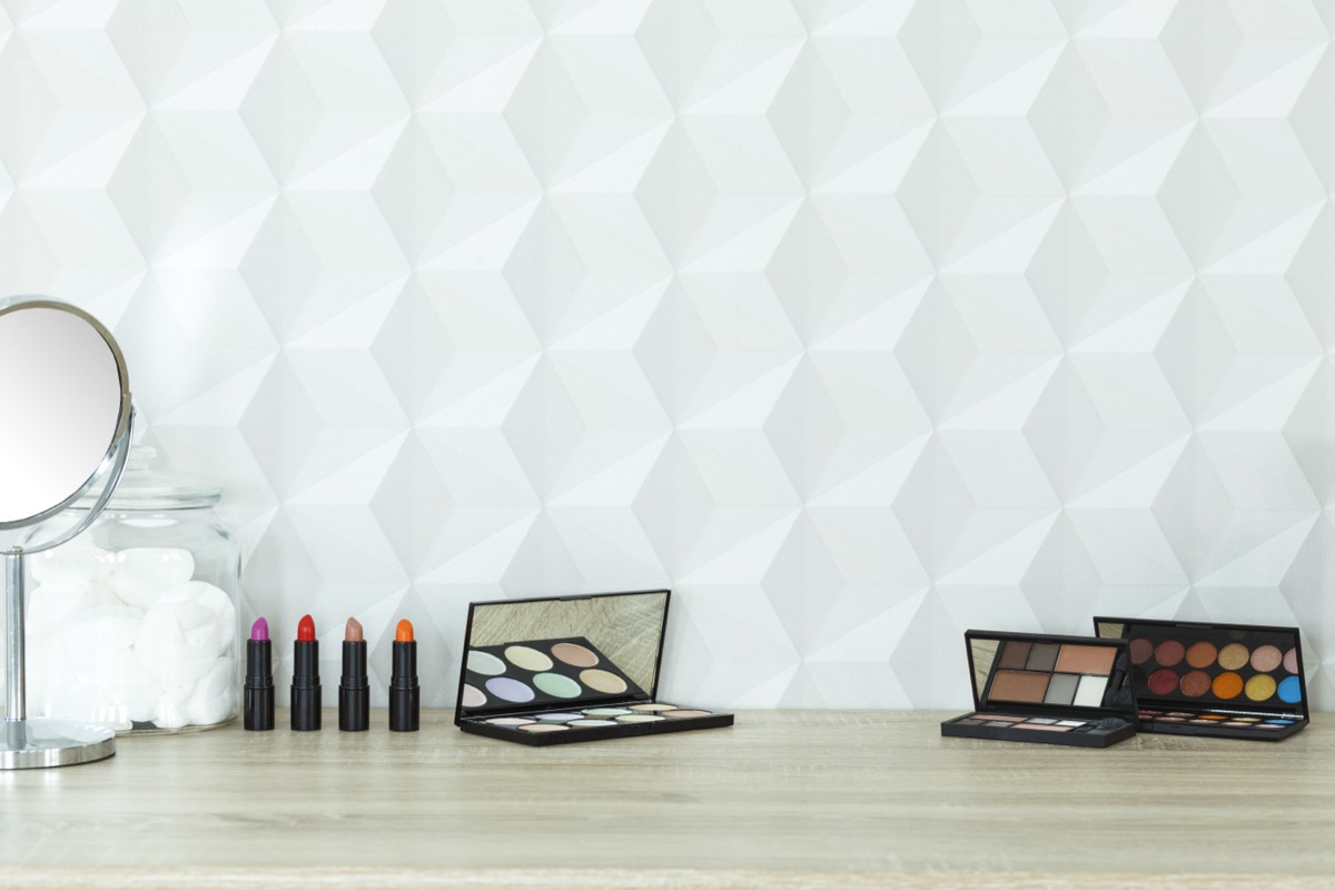 Expensive and budget cosmetics products arranged side by side for comparison on a vanity