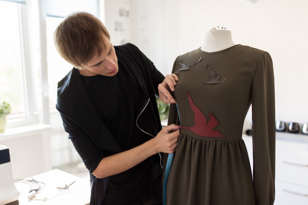 Fashion designer draping patterned fabric on a dress form in an atelier