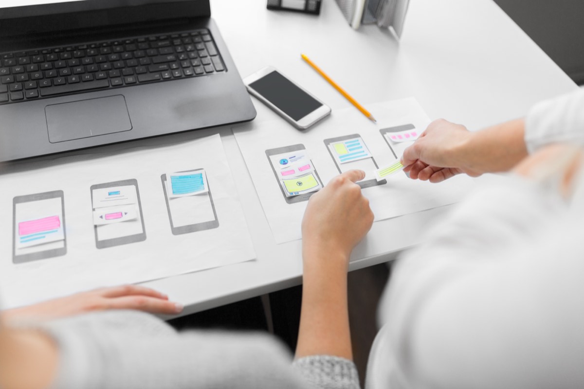 A developer reviewing mobile app code on a phone and laptop