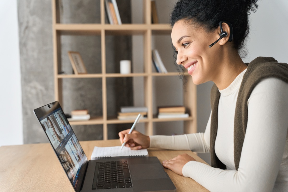 Person attending a remote video hearing on a laptop in a home office