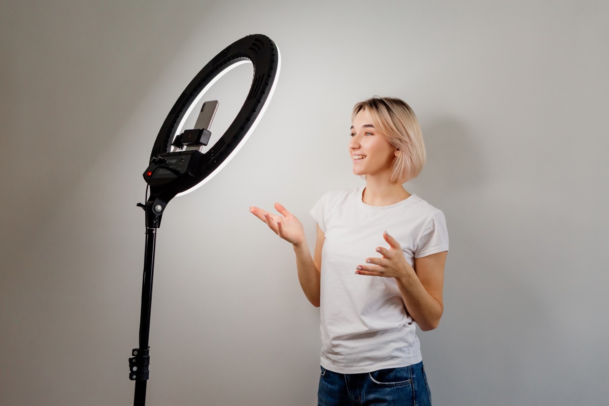 Content creator recording a video with a ring light, camera, and laptop in a home studio