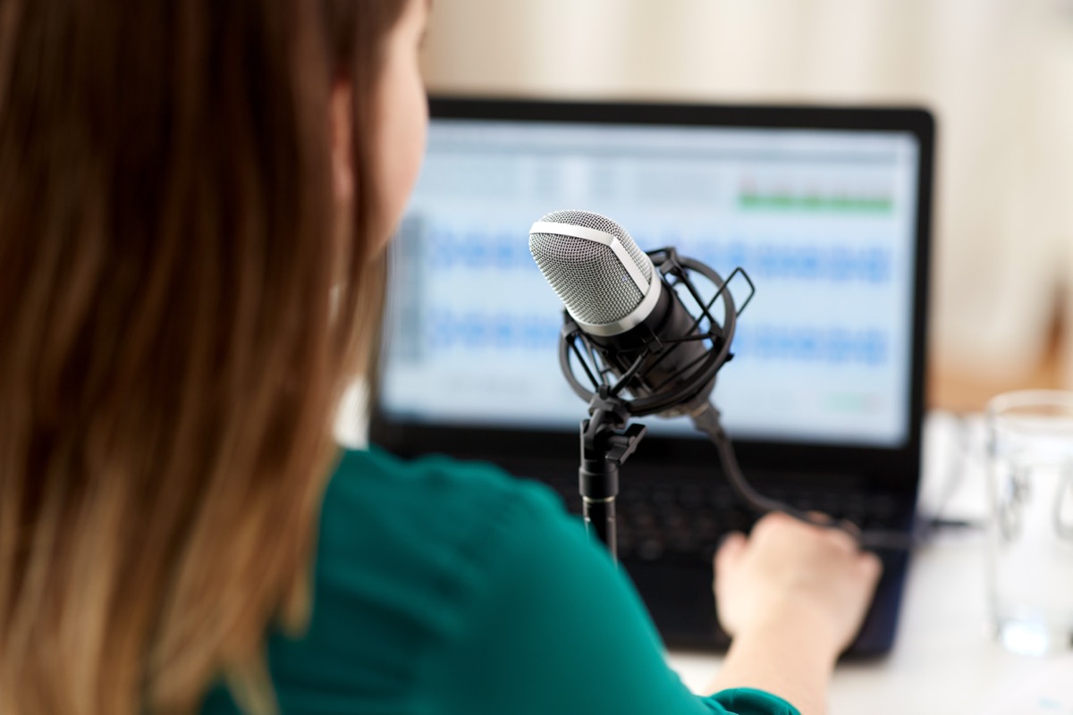 Musician recording an acoustic guitar cover song into a condenser microphone in a home studio