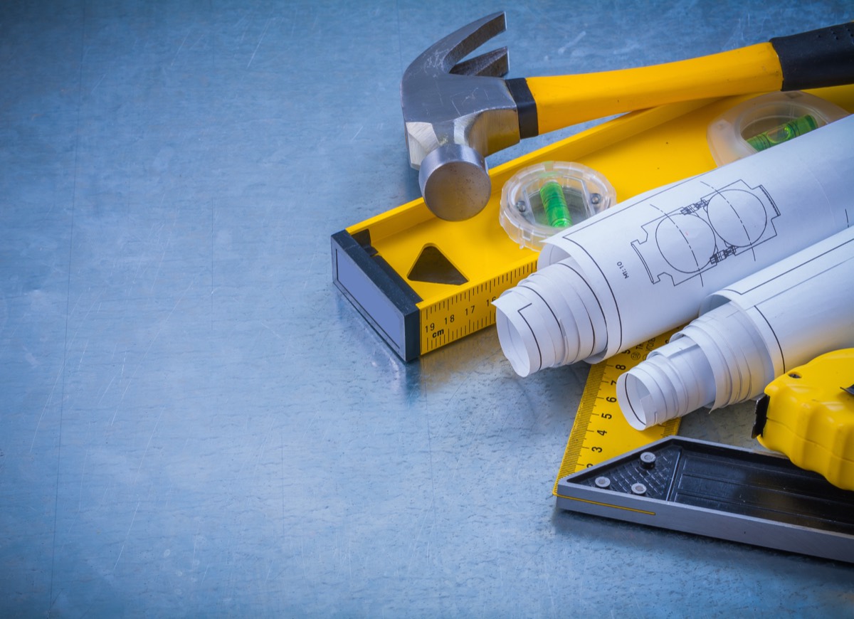 Engineer inspecting a new hardware product prototype on a workbench beside legal documents
