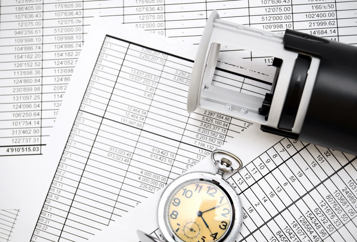 Business appraiser reviewing financial charts and patent documents spread across a desk