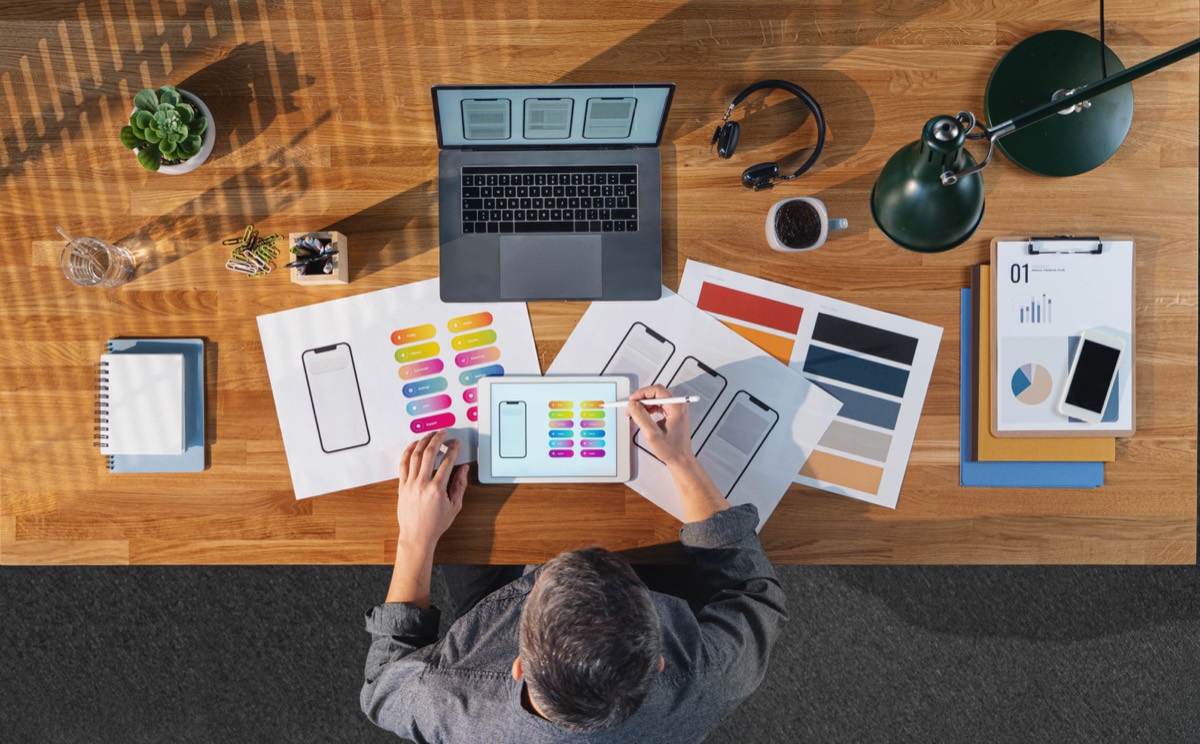 Inventor reviewing a budget spreadsheet next to a machined prototype on a workbench