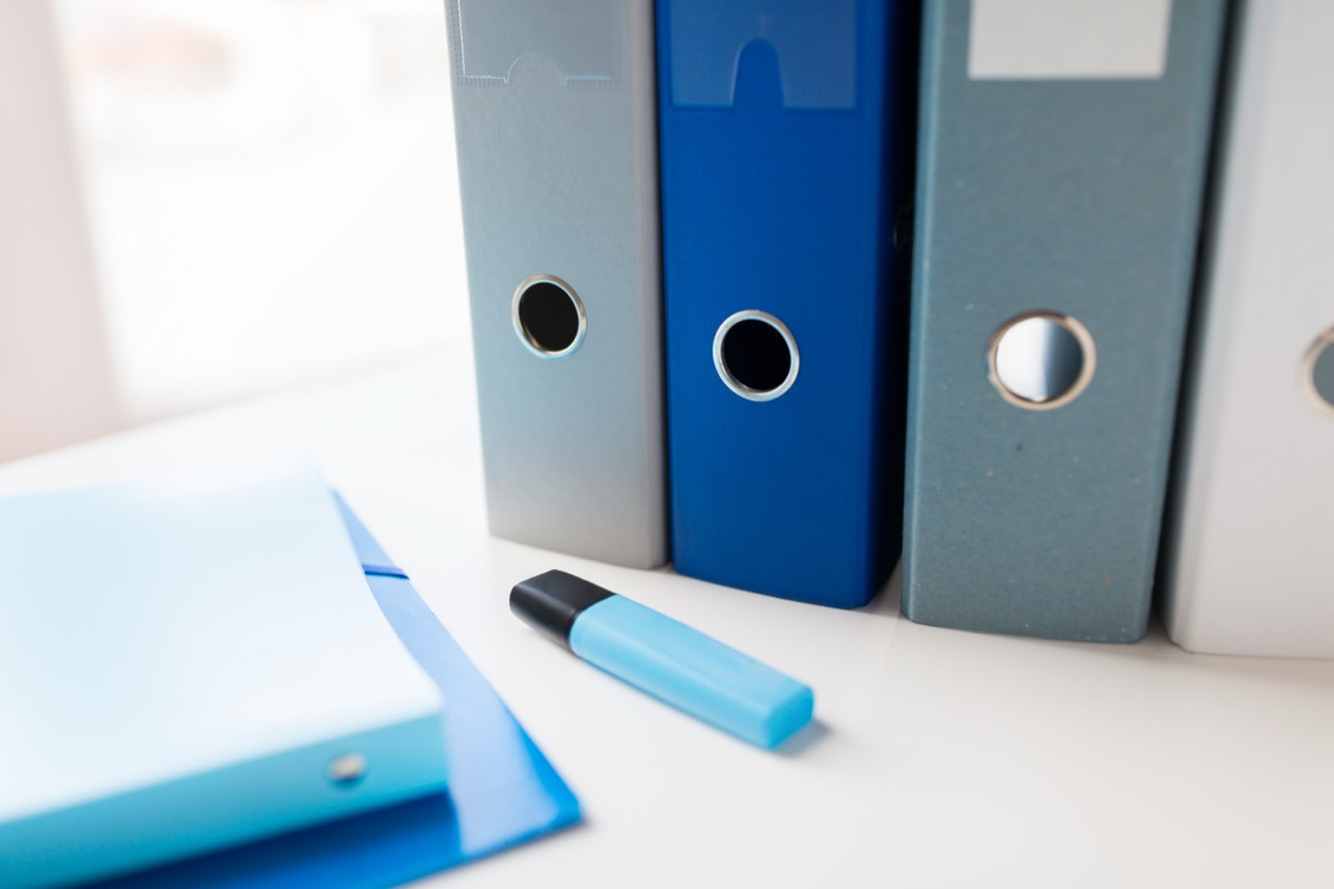 New hire reviewing a thick onboarding document stack with a highlighter at a conference table