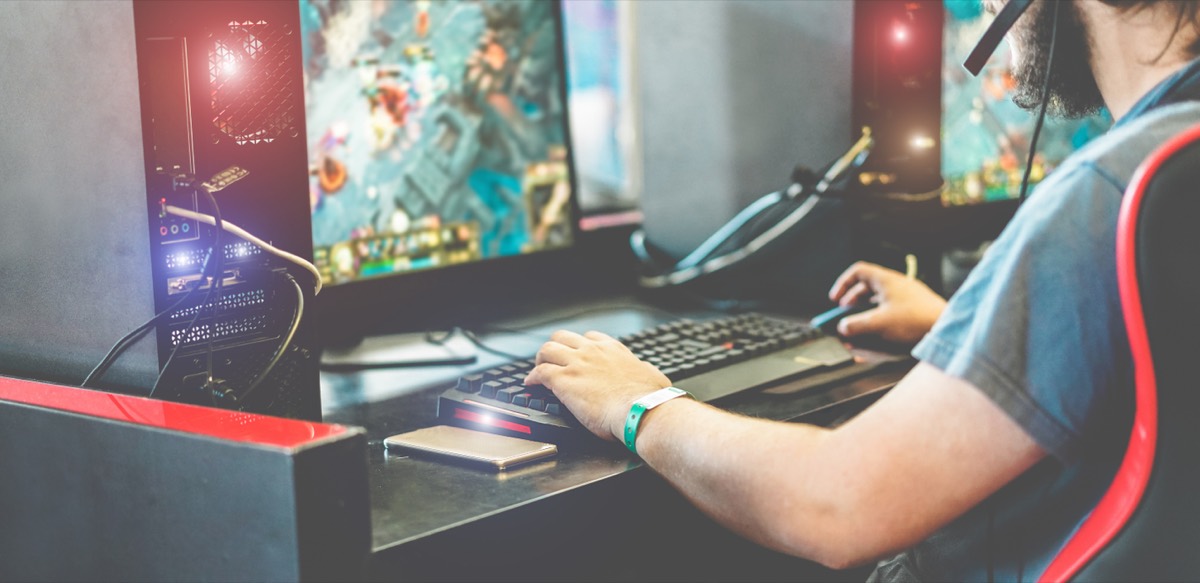 Streamer at a desk broadcasting gameplay with a microphone and RGB-lit keyboard