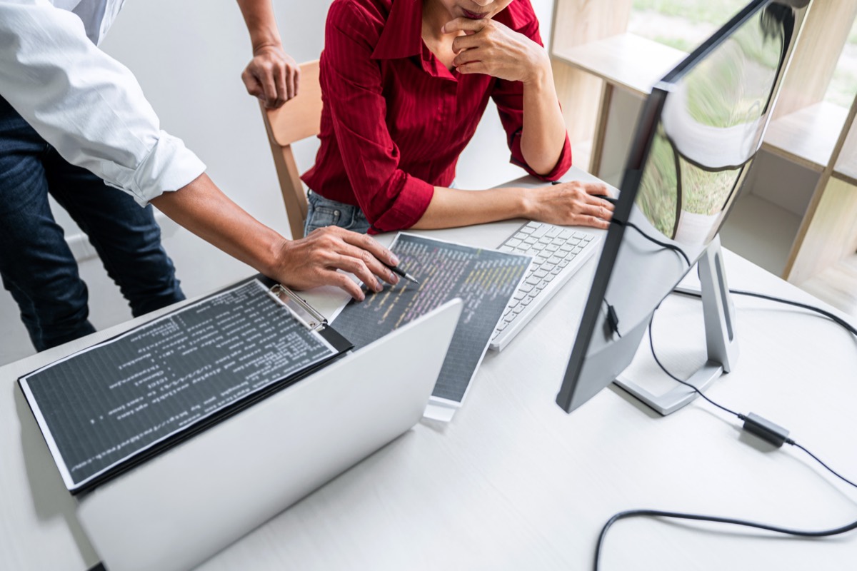 A software team reviewing code and license files on multiple monitors