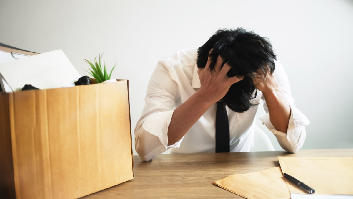 An employee packing a cardboard box of belongings at an office desk