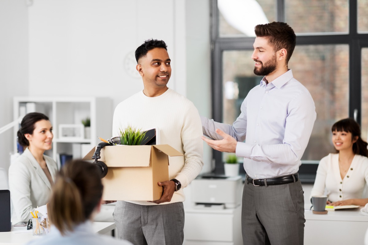 Employee carrying a cardboard box of personal belongings out of an office on their last day