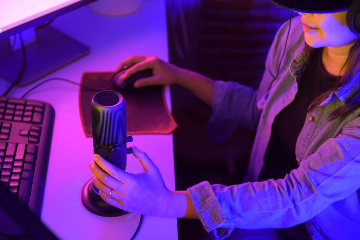 Live streamer's desk with gaming PC, boom microphone, and purple LED accent lighting