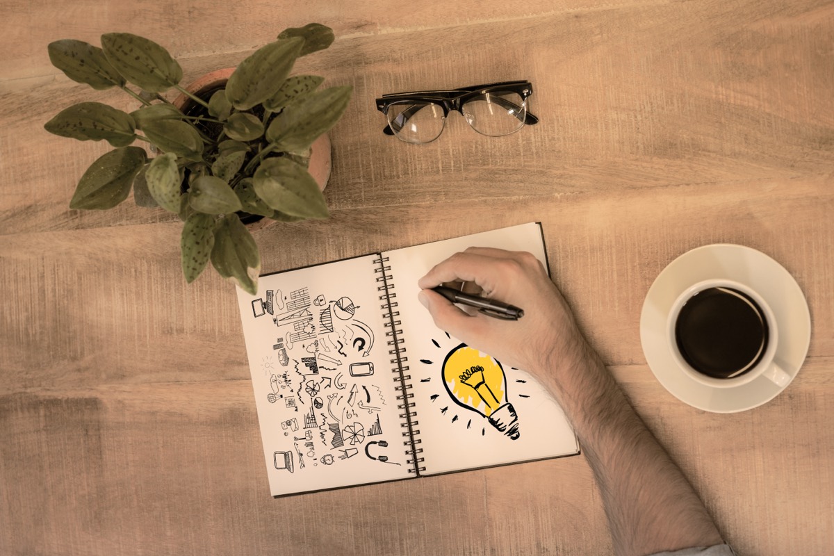 Open notebook with a lightbulb sketch next to a wooden gavel on a desk
