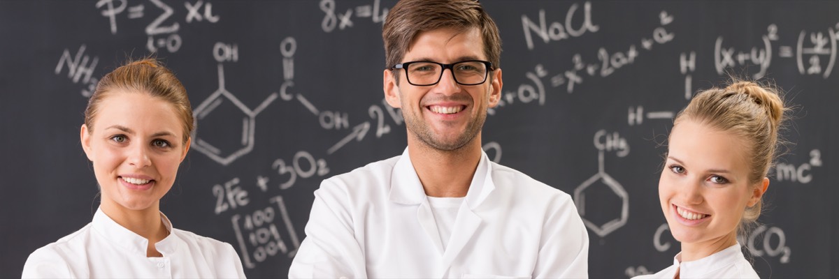 A scientist reviewing a proprietary formula on a whiteboard behind glass