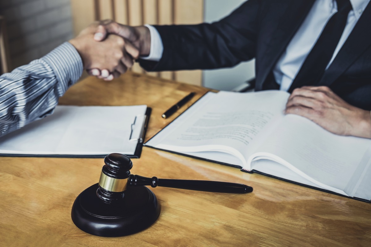 Business executive shaking hands with an attorney across a conference table with contracts