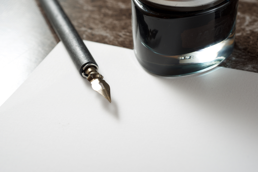 An open hardcover book with a fountain pen resting on the pages