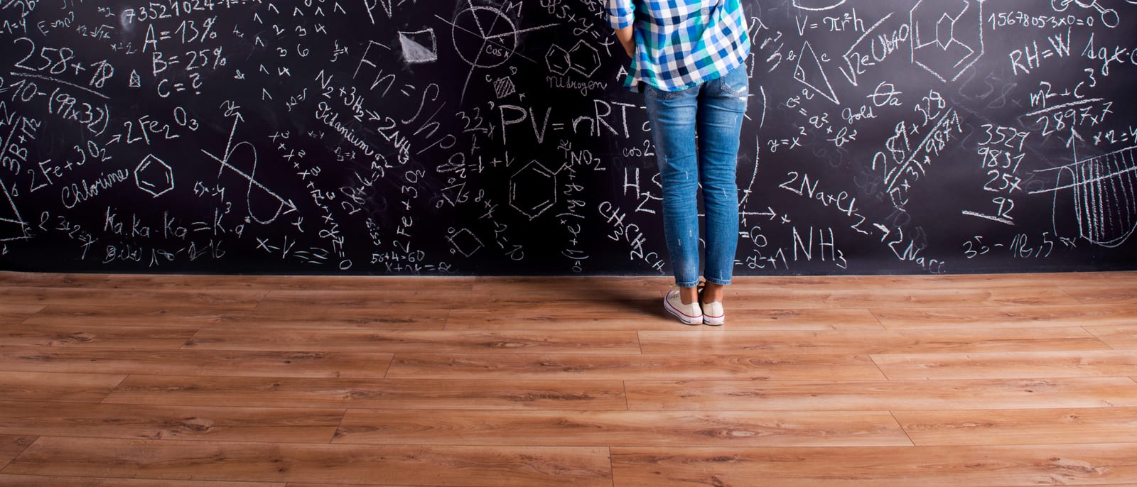 A vintage chalkboard covered in handwritten physics equations in an old lecture hall