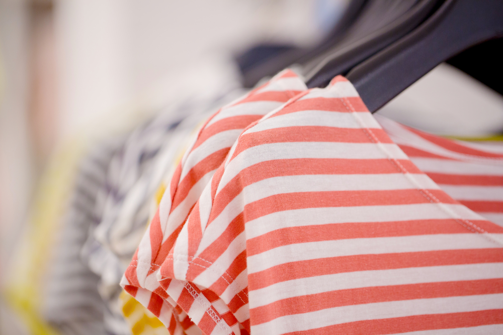 A row of folded graphic streetwear T-shirts on a retail shelf