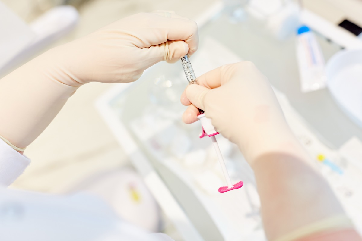 A cosmetic lip filler syringe on a clinical tray
