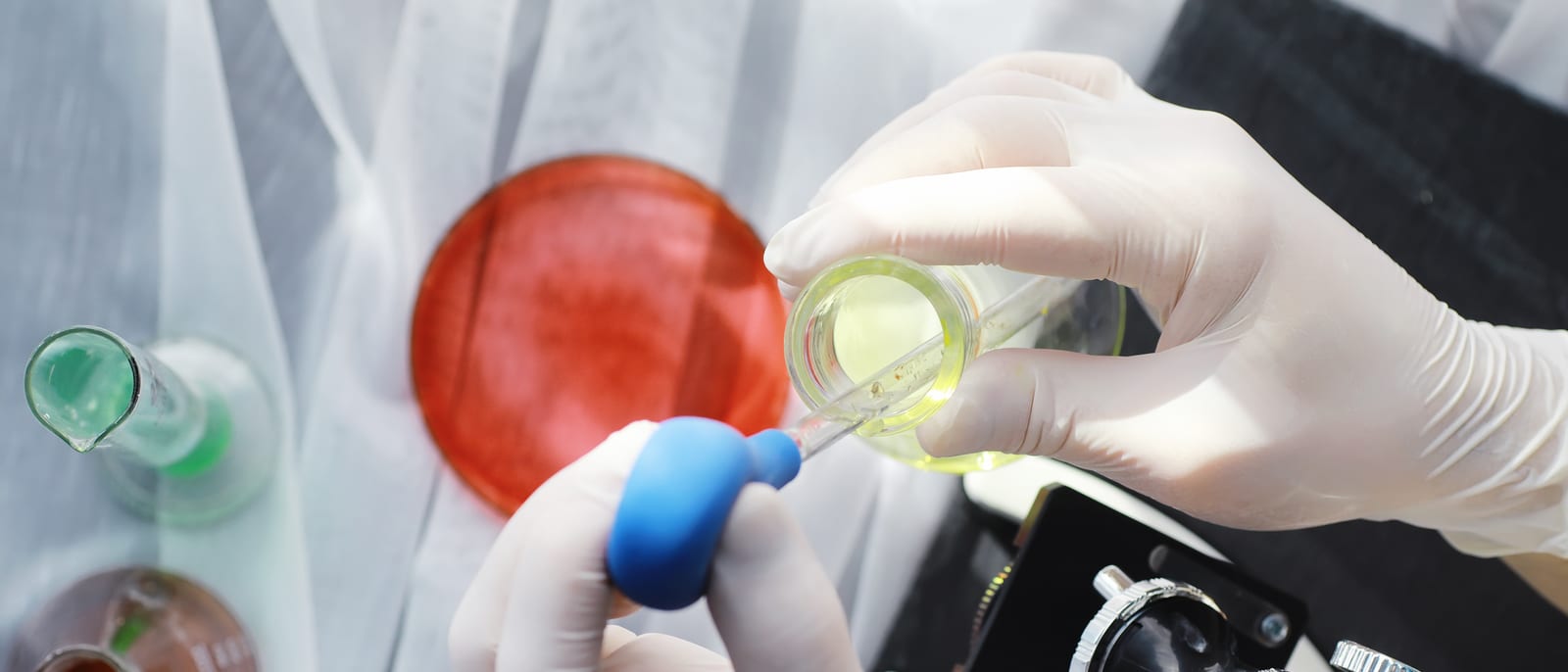 A scientist in a laboratory examining glowing apparatus through protective glass