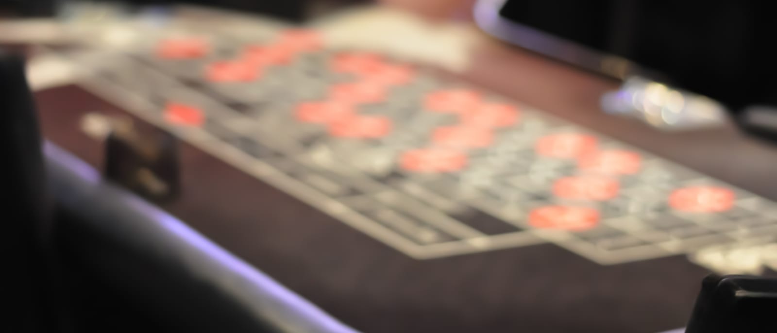 A roulette wheel and chips on a green felt casino table under warm light