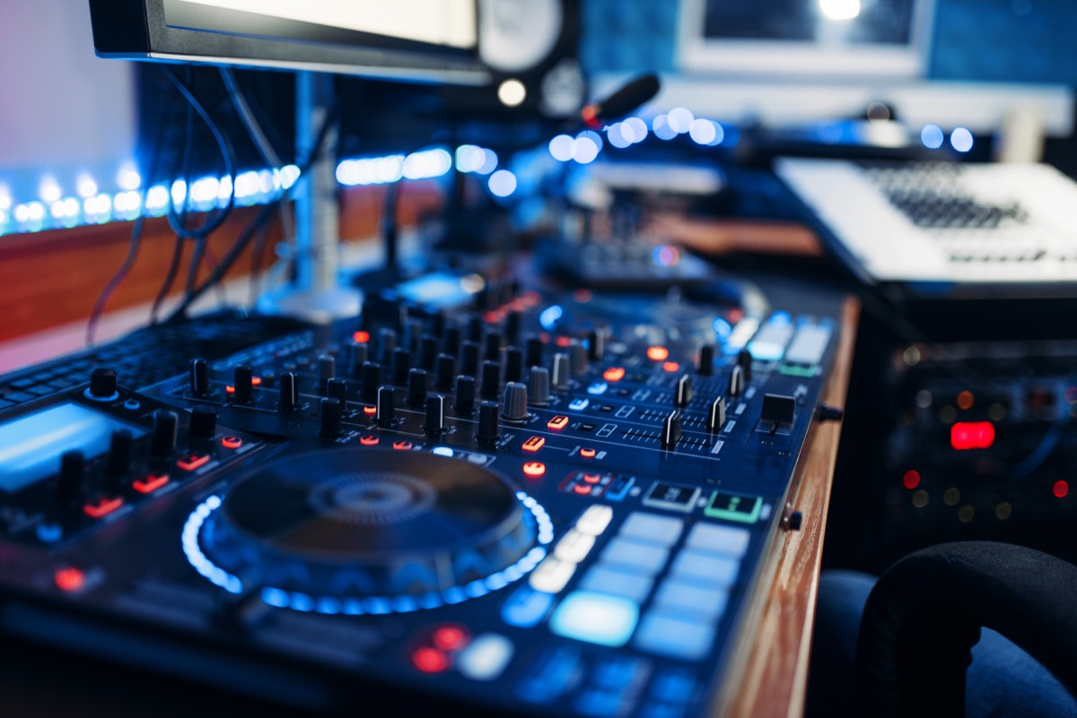 A recording studio microphone and mixing console under studio lighting