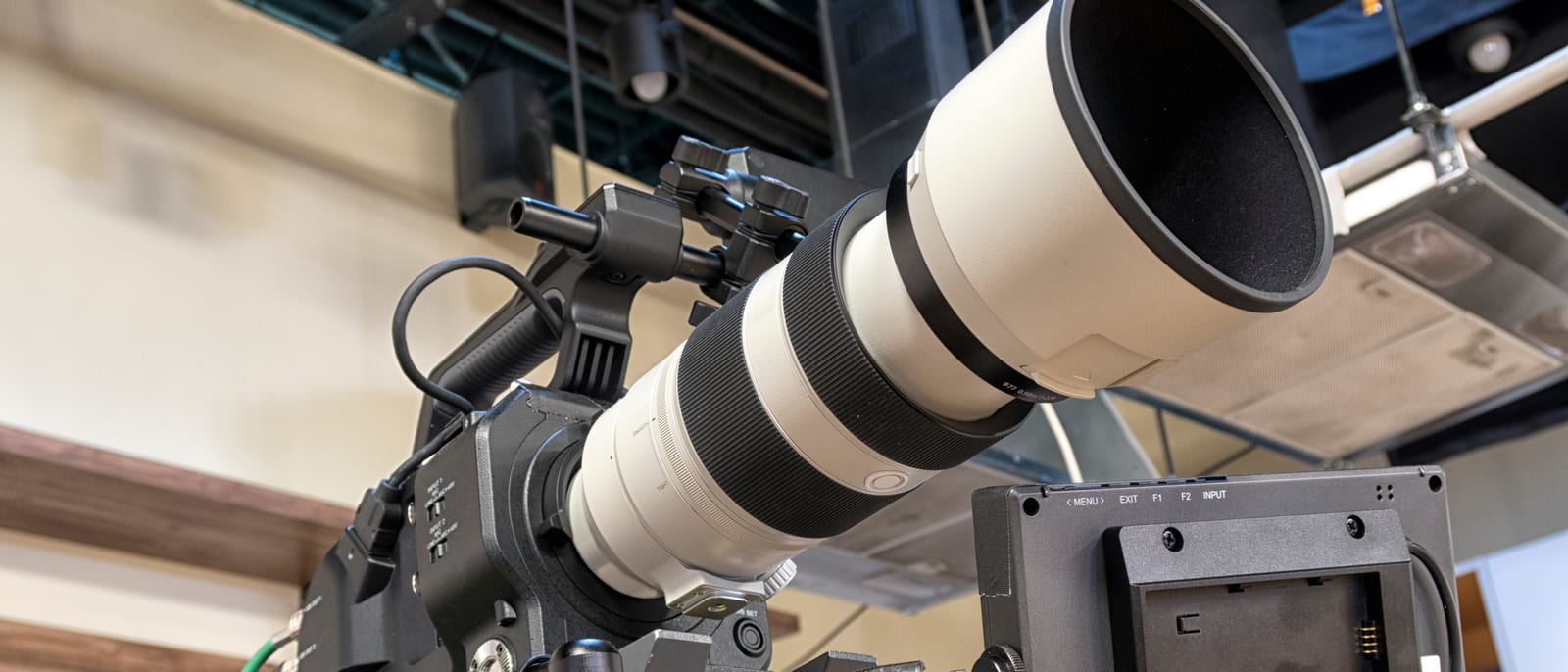 Television broadcast cameras lined up along the sideline of a packed football stadium