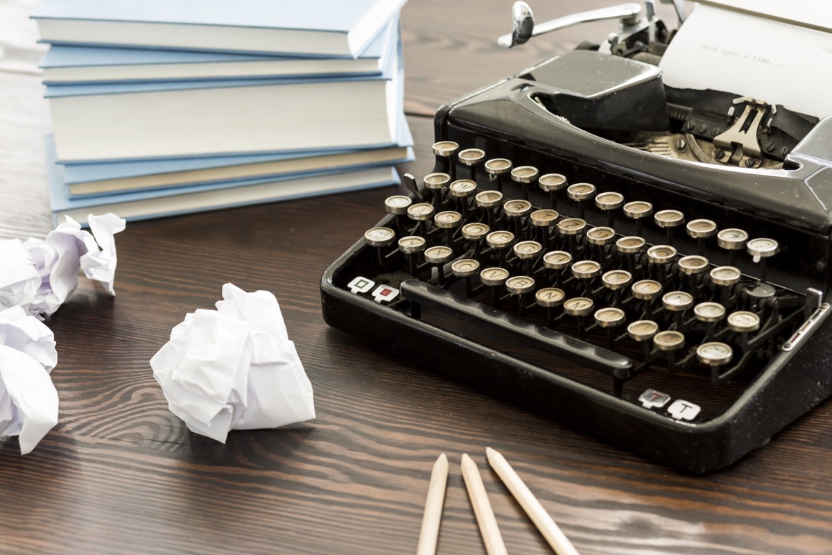 A paperback novel resting on a desk beside a typewriter