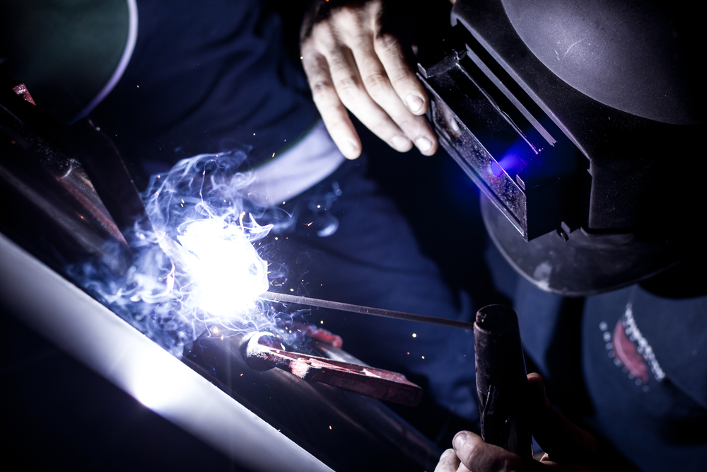 Sparks flying as a worker grinds and sprays metal in an industrial machine shop
