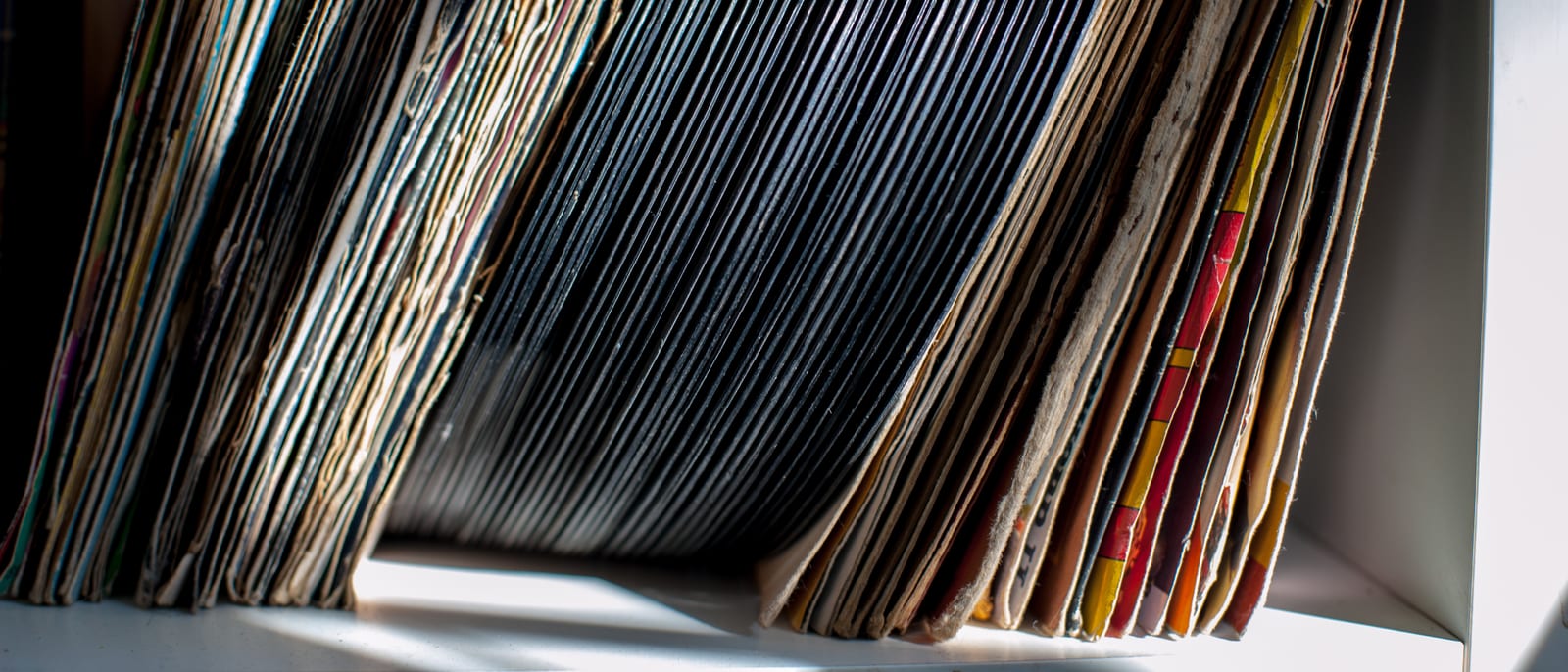 Stacks of vintage vinyl records beside a turntable in warm light