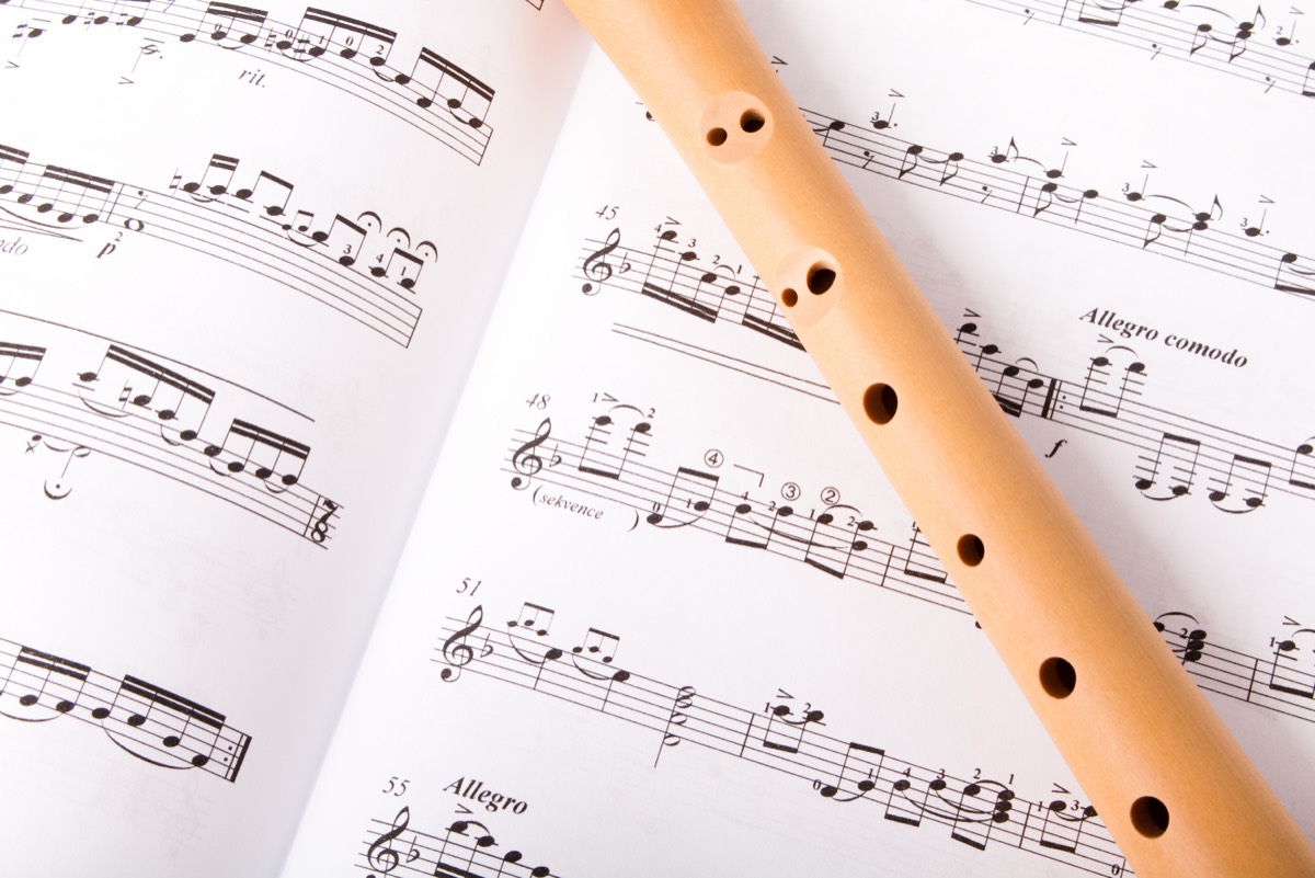 Close-up of a silver concert flute resting on printed sheet music in a recording studio